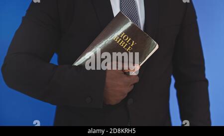 Close up, holy bible in the hands of black african american man in elegant suit. High quality photo Stock Photo