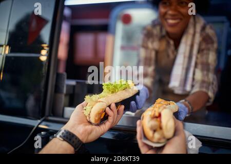 detail of hands with two different sandwiches, one with green salad and one with mustard and ketchup Stock Photo