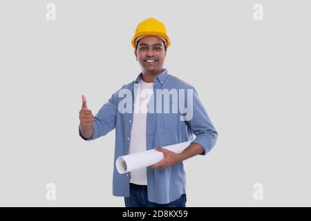 Construction Worker Holding House Plan in Hands Showing Thumb Up. Architect Holding Blueprints. Yellow Hard Helmet. Stock Photo