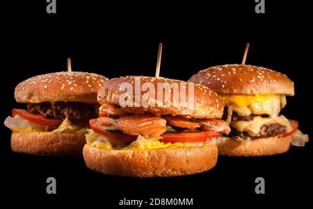 Set of different burgers isolated on black background. Hamburger, cheeseburger and fish burger. Stock Photo