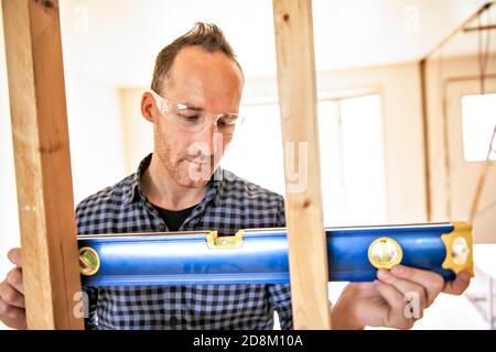 A man worker in the carpenter workroom renovation holding level Stock Photo