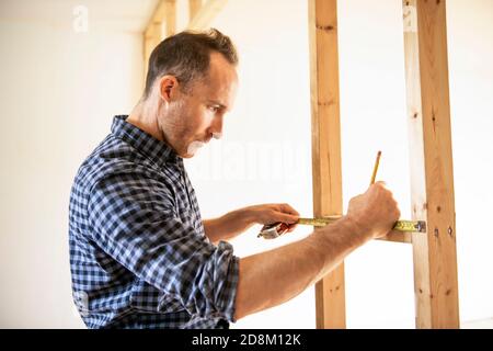 A man worker in the carpenter workroom renovation using tape Stock Photo