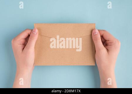 First person people above top overhead close up view photo of female woman hands holding one envelope in hands isolated over pastel color blue backgro Stock Photo