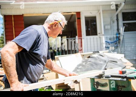 Active Older Man Working with a Saw in the Yard. Stock Photo