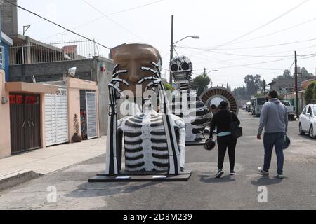 Mexico City, Mexico. 30th Oct, 2020. MEXICO CITY, MEXICO - OCTOBER 30: A person wears face mask while walks front a monumental skull made of cardboard, were put to decorate the streets Of Tlahuac to celebrate Day of the Dead ( Dia de Muertos) amid Covid-19 pandemic. on October 30, 2020 in Mexico City, Mexico. Credit: Ismael Rosas/Eyepix Group/The Photo Access Credit: The Photo Access/Alamy Live News Stock Photo