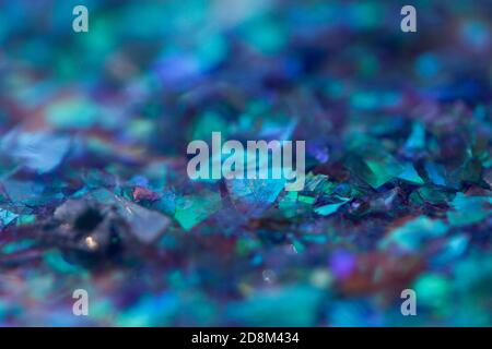 Abstract blurred blue toned background with beautiful bokeh effect. Macro photo of small rainbow glossy pieces of decorative foil in blue shades. Stock Photo