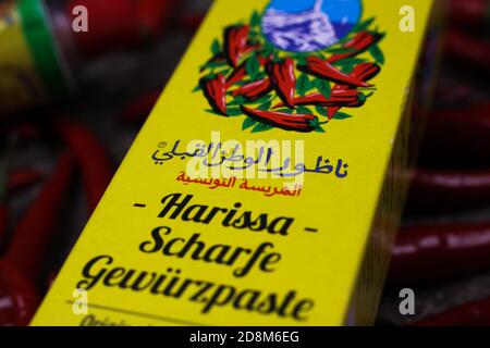 Viersen, Germany - October 9. 2020: View on yellow packet tunisian harissa spice paste tube with red chillies background Stock Photo