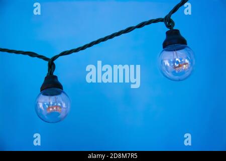 Hanging light two bulbs with glowing one different idea on light blue background. Stock Photo
