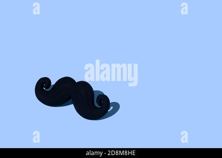 Minimal composition with black mustache on a blue background with place for inscription. Hard light. Prostate cancer awareness concept photo. Stock Photo