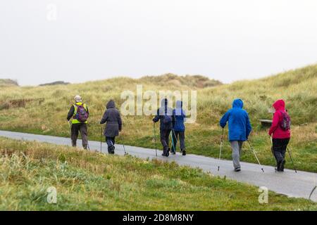 Elderly walkers on group outing using nordic poles in Crosby, Merseyside.  UK Weather. October, 2020.  Strong winds and heavy rain on the Liverpool Estuary.   Credit: MediaWorldImages/AlamyLiveNews. Stock Photo
