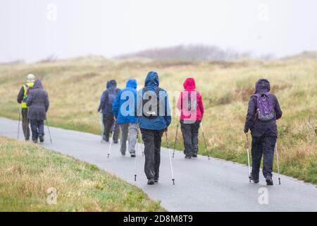 Elderly walkers on group outing using nordic poles in Crosby, Merseyside.  UK Weather. October, 2020.  Strong winds and heavy rain on the Liverpool Estuary.   Credit: MediaWorldImages/AlamyLiveNews. Stock Photo