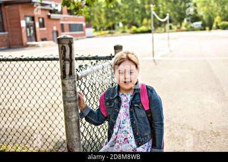 A portrait of trisomie 21 child girl outside on a school playground Stock Photo