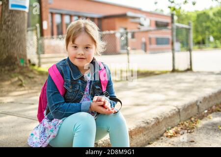 A portrait of trisomie 21 child girl outside on a school playground Stock Photo