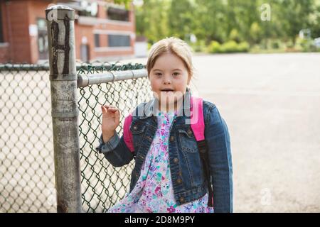 A portrait of trisomie 21 child girl outside on a school playground Stock Photo