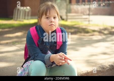 A portrait of trisomie 21 child girl outside on a school playground Stock Photo