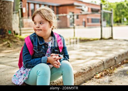 A portrait of trisomie 21 child girl outside on a school playground Stock Photo