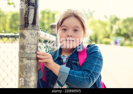 A portrait of trisomie 21 child girl outside on a school playground Stock Photo