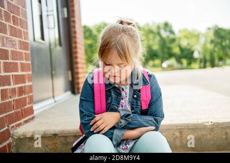 A portrait of trisomie 21 child girl outside on a school playground Stock Photo