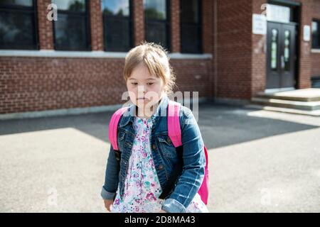 A portrait of trisomie 21 child girl outside on a school playground Stock Photo