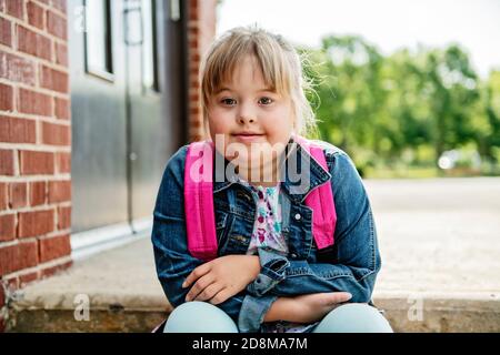 A portrait of trisomie 21 child girl outside on a school playground Stock Photo