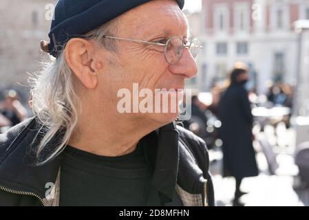 Portrait of an elderly long white haired artist wearing glasses and black hat in the square. Stock Photo