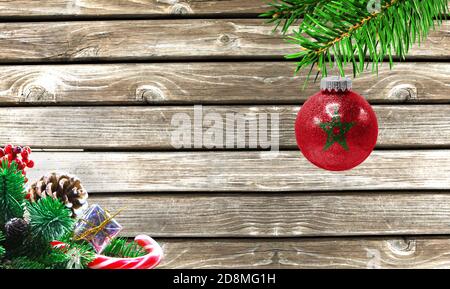Concept of New Year and Christmas, on a wooden background, Christmas tree branches and a Christmas toy with the flag of Morocco. Stock Photo