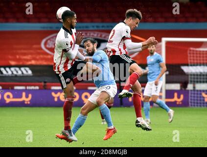 Manchester City's Bernardo Silva battles for the ball with Sheffield United's Max Lowe (left) and Ethan Ampadu (right) during the Premier League match at Bramall Lane, Sheffield. Stock Photo