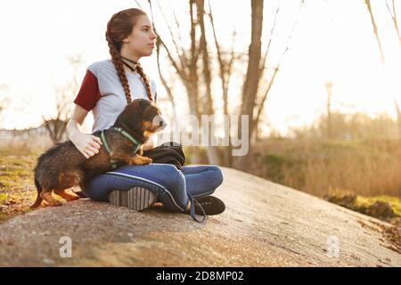 young woman next to her dog in the park at sunset Stock Photo