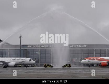 31 October 2020, Berlin, Schönefeld: Aircraft belonging to the airlines Lufthansa and Easyjet stand after landing under a fountain of water from the airport fire brigade in front of Terminal 1 of the capital airport Berlin Brandenburg 'Willy Brandt' (BER). The airport will open on 31.10.2020 after a long delay. Photo: Michael Kappeler/dpa
