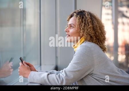 Side portrait of beautiful african american woman holding mobile phone and looking up Stock Photo