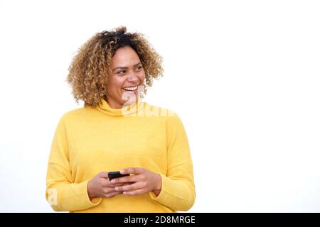 Portrait of young african american woman holding cellphone and looking away by white background Stock Photo
