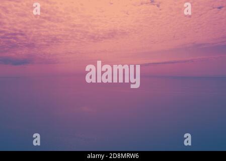 Beautiful sunset over the sea. Sunbeams coming from behind the clouds. Colorful nature sea sky with red and orange gradient. Stock Photo