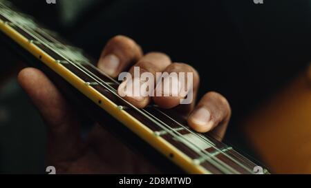 left hand playing guitar on the fretboard Stock Photo