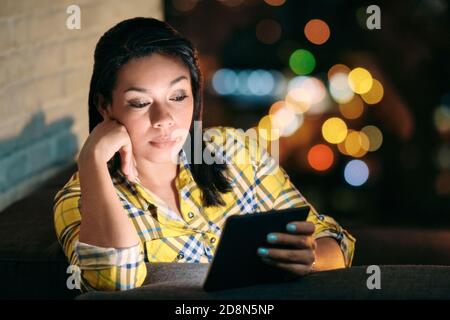 Young Woman Holding Ereader And Reading Ebook At Night Stock Photo