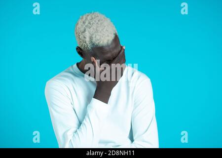 Portrait of young african man doing facepalm gesture, like no, I forgot. Unhappy black guy feeling sorrow, regret, drama, failure. He isolated on blue Stock Photo