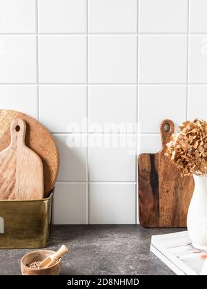 Stylish white kitchen background with brown kitchen utensils and decor standing on textupe grey countertop, copy space, front view Stock Photo