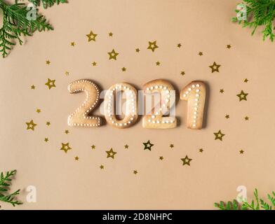 Gingerbread cookies in the form of numbers, gingerbread New Year 2021 on beige background. Top view. Confetti gold stars Christmas decor. Stock Photo