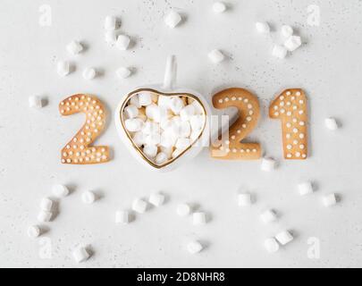 Gingerbread cookies in the form of numbers, gingerbread New Year 2021 and mug with hot drink and marshmallows instead of scratch on light background . Stock Photo