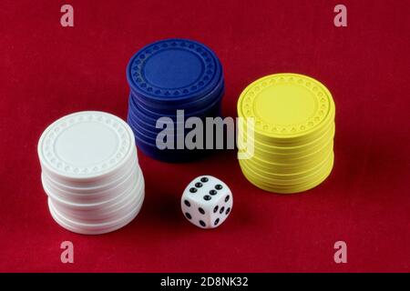 Coloured gambling chips and white die on a red background Stock Photo