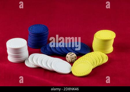 Coloured gaming chips and die on a red background Stock Photo