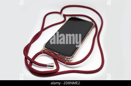 Smartphone in transparent case crossbody with red long textile strap, comfortable usage of mobile phone protective accessory Stock Photo