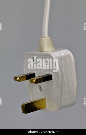 a replaceable white 3 pin electric plug (type G) containing a replaceable fuse for mains 240 volts (UK specification) suspended by its cable Stock Photo