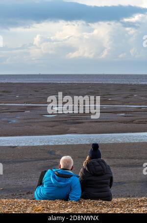 a young couple spending time together birwatching on the beach in snettisham north nofolk in the romantic evening light sharing a hobby Stock Photo
