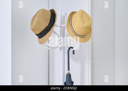 Stylish hats, umbrella hanging on floor hanger in the hallway Stock Photo