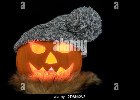 Carved halloween pumpkin with scarf and knitted hat isolated on a black background Stock Photo