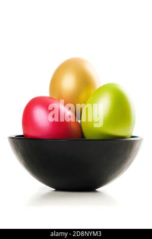 Group of colored Easter Eggs in saucer on white background. A bunch of pearl colored easter eggs in black saucer isolated on white with shadow. Studio Stock Photo