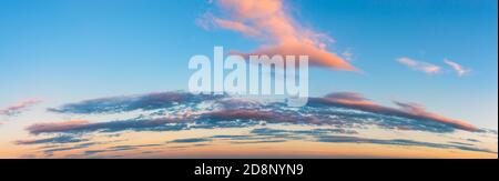 Vanilla sunset sky panoramic shot. Pink golden blue evening sky with long stratus clouds over the horizon. Pastel colored calm skyscape. Stock Photo