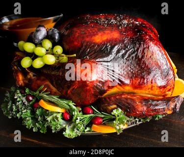 Maple Cider Bourbon Brined Turkey with Bourbon Gravy: A large turkey served on a platter with garnishes and gravy Stock Photo