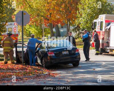 Oak Park, Illinois, USA. 31st October 2020. Police, a paramedic, a firefighter and a bystander attend to the driver of an automobile involved in an accident. Stock Photo