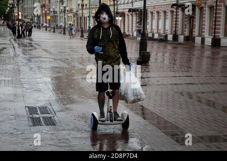 Moscow, Russia. 10th of June, 2020 A young man wearing face mask carries food on a self-balancing electric scooter from a grocery store on Arbat street in the center of Moscow during the novel coronavirus COVID-19 pandemic in Russia Stock Photo